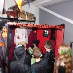 Young people in Halloween costumes gathered around a witch's house.