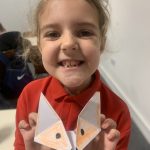 Happy young person holding their origami craft.