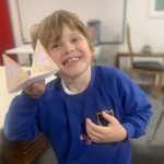 A happy young person holding the craft they have made.