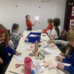 A young Arts and Crafts club attendee showing the rest of Arts and Crafts club how to make and origami craft.