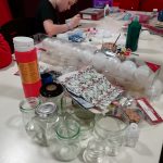 A selection of Craft materials and a young person painting.