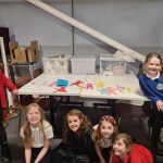 Happy young people from Arts and Crafts club gathered around a table with their handmade
