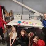 Happy young people from Arts and Crafts club gathered around a table with their handmade