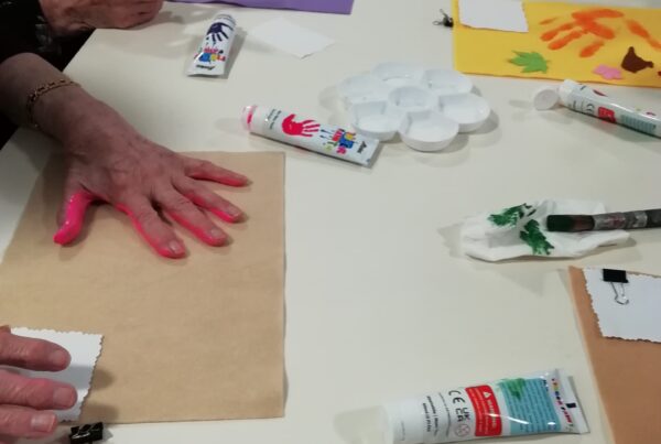 People making handprints on felt on a table.