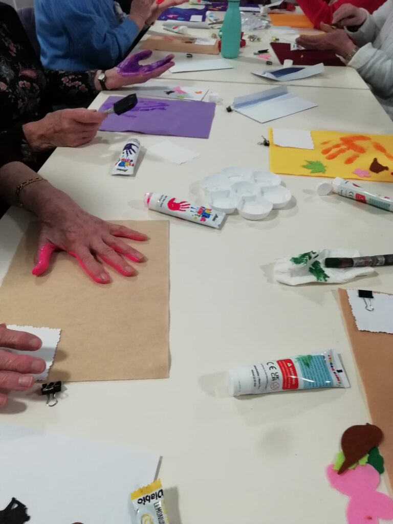 People making handprints on felt on a table.