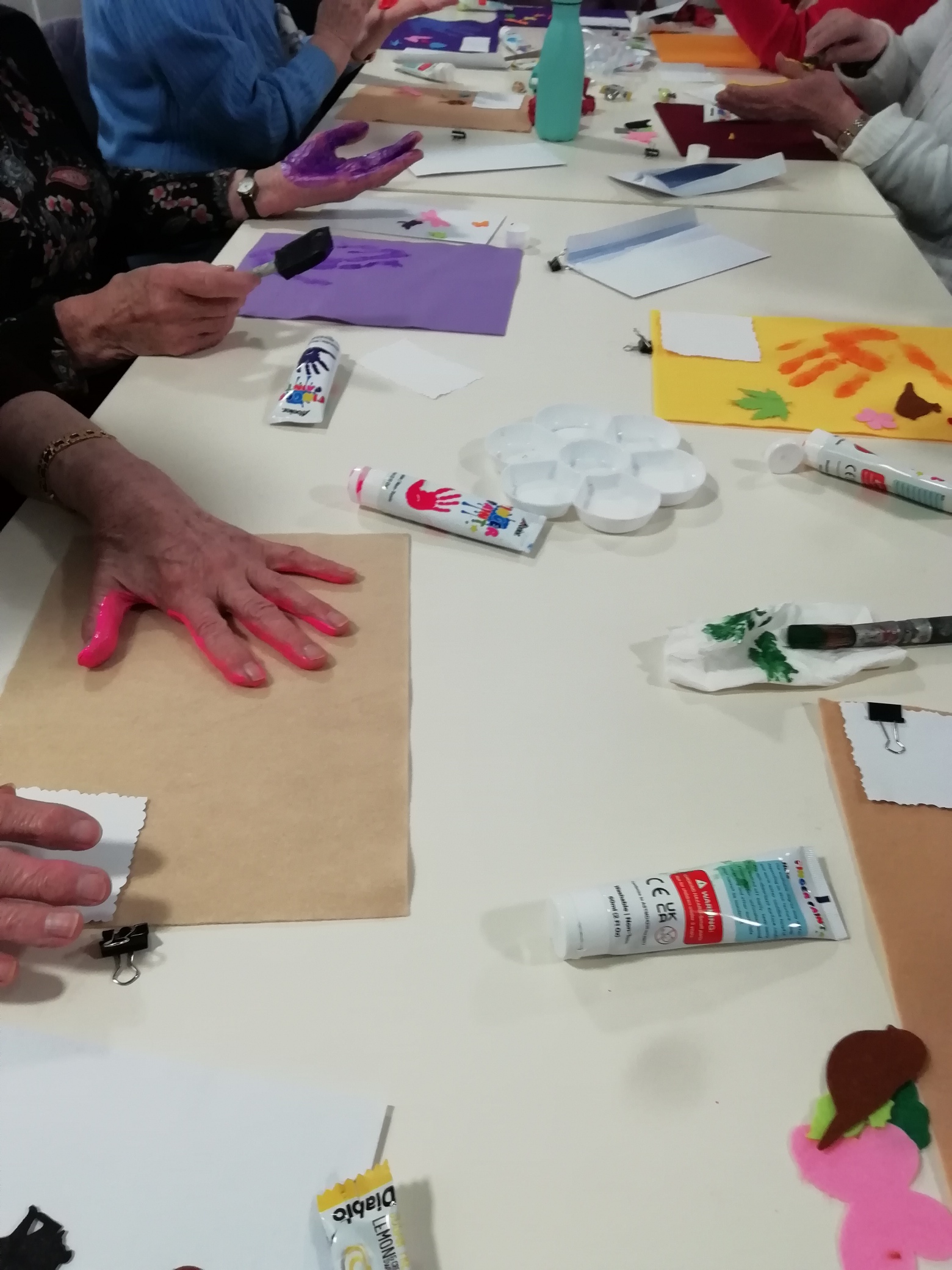 People making handprints on felt on a table.
