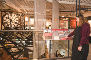 A person reading some information about the Mossband clock, which is on display inside The Devil's Porridge Museum.