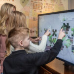 A family using an interactive display inside The Devil's Porridge Museum.