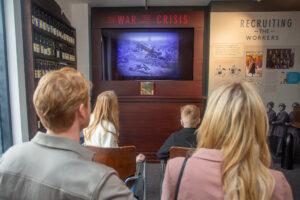 A family watching a video inside The Devil's Porridge Museum.