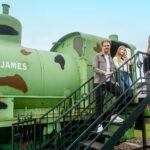 A family stood on some stairs beside fireless locomotive, Sir James.