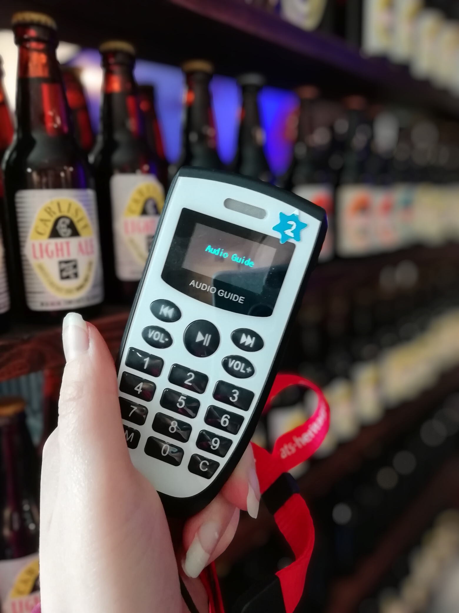 A handheld audio guide. There are some bottles display in the background.