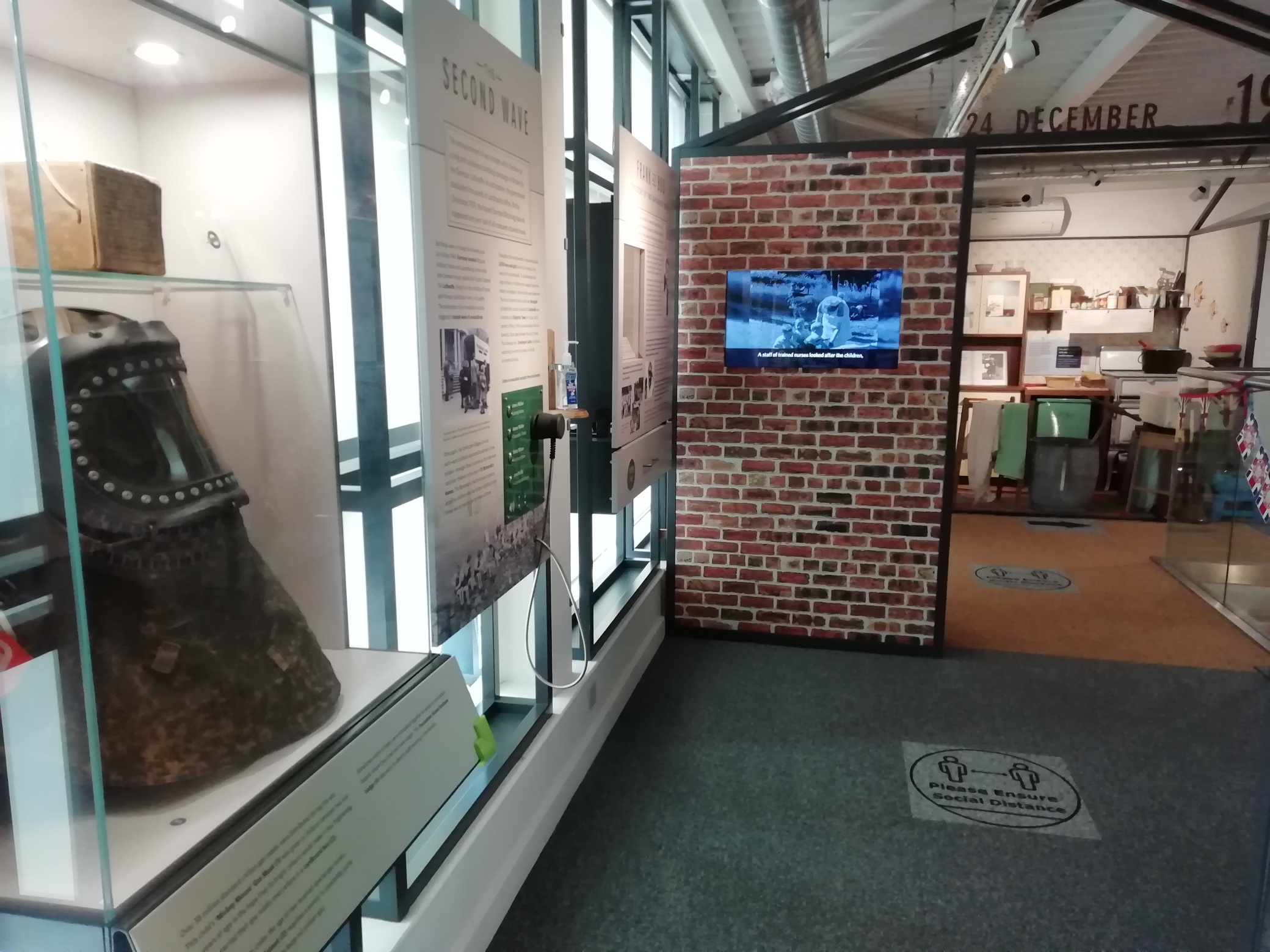 Upstairs in The Devil's Porridge Museum with a gas mask and a video with subtitles on display. The 1940s house display can be seen in the background.