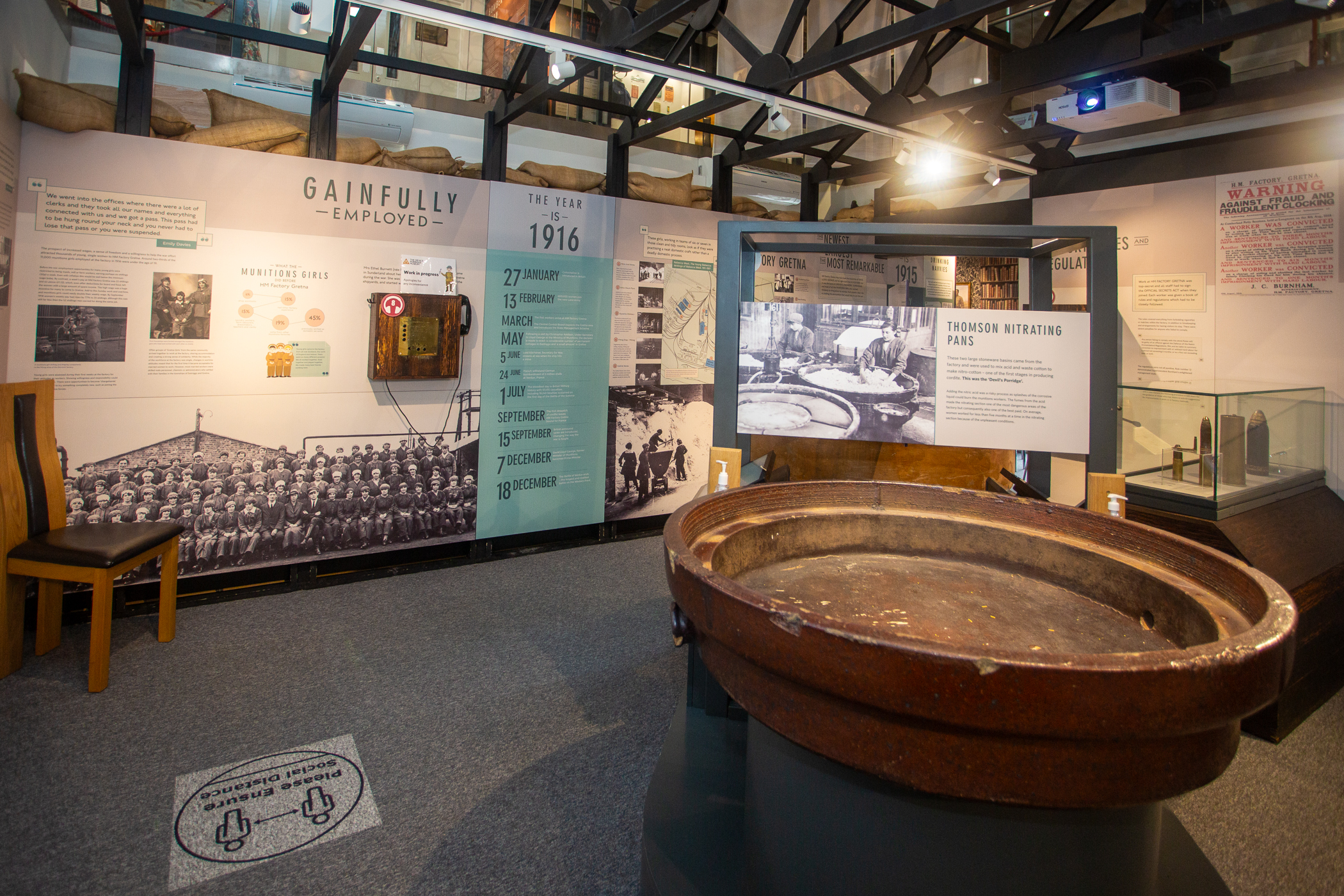 Inside The Devil's Porridge Museum. One of the nitrating pans or porridge pots can be seen on display and there is a chair to one side.