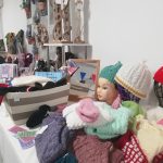 A selection of handknitted items, including hats, made by the Scotia Crafters on display on a table inside The Devil's Porridge Museum's education room.
