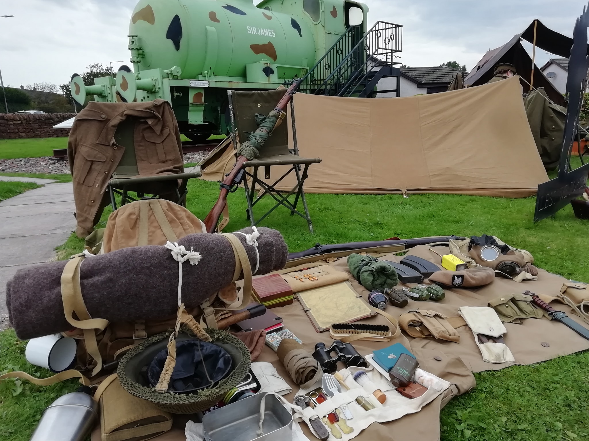 World War Two military items displayed on the grass in front of Sir James. Sir James is a World War One fireless locomotive.
