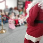 Santa stood facing some children in The Devil's Porridge Museum's education room. The photo is blurred so you can't see the faces of the children.