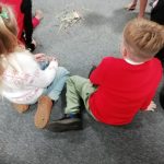 Children sat in a circle playing pick up sticks on the floor.