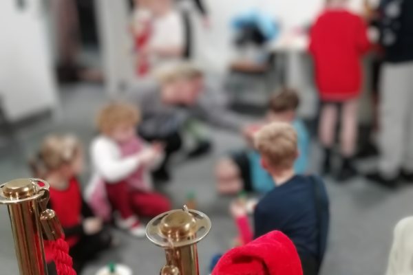 Children's Christmas Party 2025 5. Children sat on the floor eating in The Devil's Porridge Museum's education room.