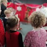 Some young people gathered around looking at Santa.