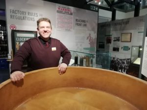 Tom, The Devil's Porridge Museum's Youth and Community Engagement Officer stood next to a nitrating pan inside The Devil's Porridge Museum.