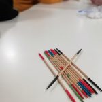 Pick up sticks arranged on a table with some members of Cordite Club in the background.