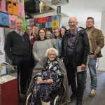 One hundred and four year old Helen with her family stood around her inside The Devil's Porridge Museum. They all look happy.