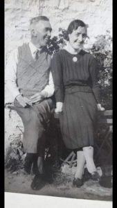Charles and Annie Corrin sat together on a bench. They look happy. This is a photo from the past.
