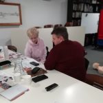 Four members of The Devil's Porridge Museum's team gathered around a table. First Aid instructor Stuart Rob is preforming CPR on a model in the background.