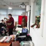 The Devil's Porridge Museum's Youth and Community Engagement Officer, Tom stood playing the bagpipes. The table behind him is covered with World War Two related items. Young museum volunteer Scott is also sat in the background.