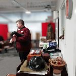 The Devil's Porridge Museum's Youth and Community Engagement Officer, Tom stood playing the bagpipes. The table behind him is covered with World War Two related items.