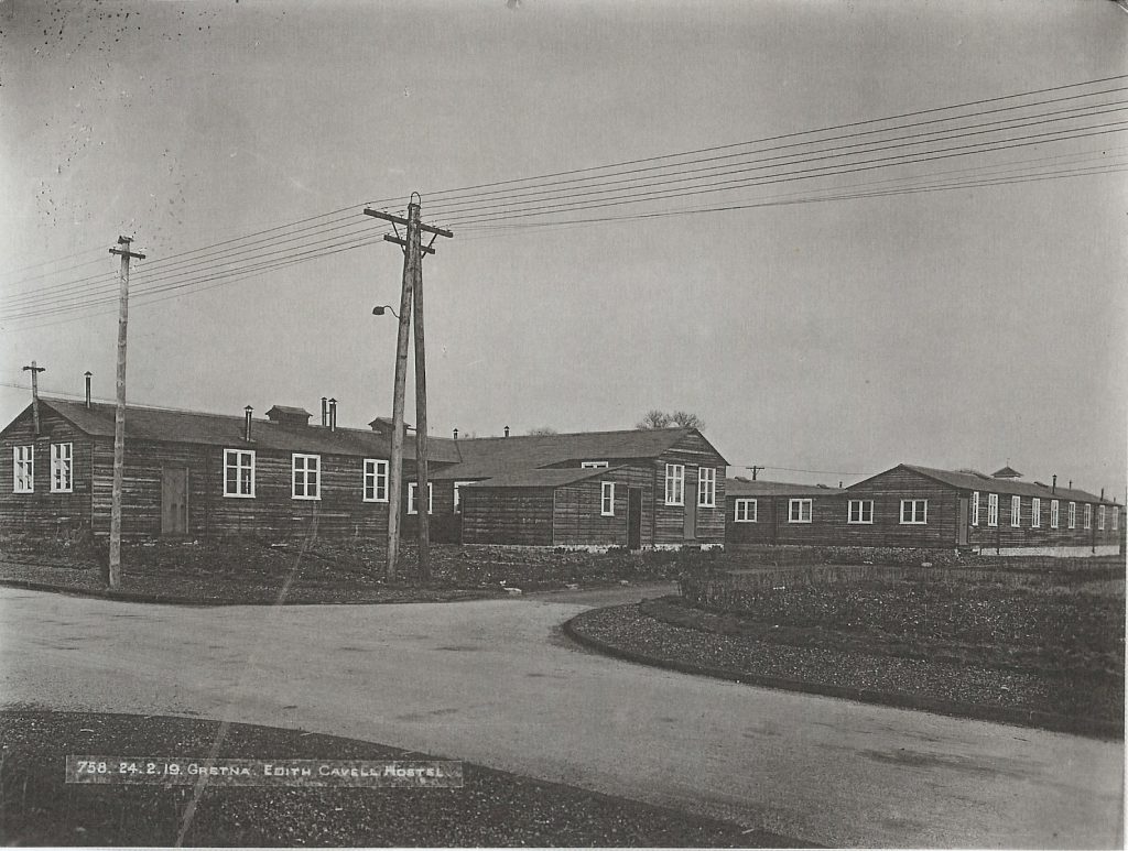 Some wooden hostel buildings in Gretna next to a road. Some text at the bottom of the photo reads "21. Gretna - Edith Cavell Hostel." This is a black and white archive photo from the past.