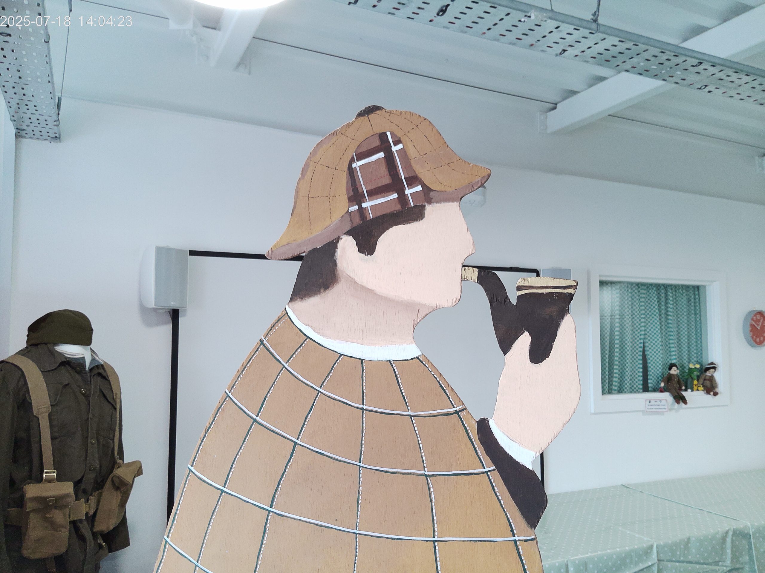 A wooden cut out of Sherlock Holmes holding a pipe and wearing a hat