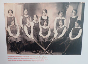 The Dornock women's hockey team arranged in two rows. Two of the members are holding hockey sticks.